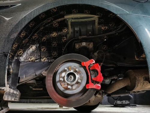 Wygłuszanie nadkola w Fordzie Mustang Bullit czarną matą alubutylową Bitmat, widoczna tarcza hamulcowa