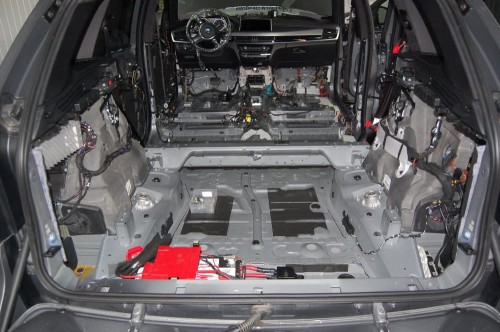 Zdemontowane wnętrze BMW X5, na podłogę naklejana jest pierwsza warstwa alubutylowej maty wygłuszającej Bitmat