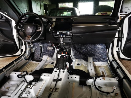 Wnętrze kabiny Hondy Civic X z widoczną gołą blachą podłogi przygotowane do aplikacji izolacji akustycznej Bitmat