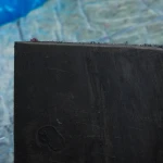 Zbliżenie na przekrój samoprzylepnego produktu 2w1, wyraźnie odcinająca się warstwa czarnej gumy i grubego filcu.