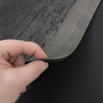Dłoń wyginająca arkusz gumy wygłuszającej, prezentująca wysoką elastyczność materiału.
