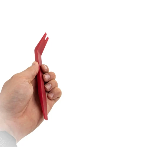 Dłoń prezentująca czerwony, plastikowy ściągacz z widełkami do precyzyjnego wyciągania spinek tapicerskich.