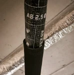 Pionowy odcinek rury instalacyjnej szczelnie pokryty matą butylową i pianką poliuretanową pochłaniającą.