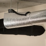 Zbliżenie na rurę zabezpieczoną aluminiowym płaszczem ochronnym, stanowiącym barierę termiczną i mechaniczną.