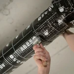 Rozwałkowywanie maty butylowej metalowym wałkiem
