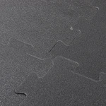 Zbliżenie na precyzyjne łączenie dwóch elementów ciemnoszarej maty piankowej typu puzzle.