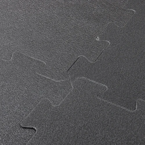 Zbliżenie na precyzyjne łączenie dwóch elementów ciemnoszarej maty piankowej typu puzzle.