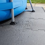 Zbliżenie na metalową stopę stelaża basenu, która opiera się stabilnie na podkładzie z maty piankowej.
