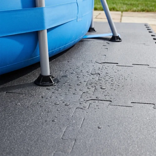 Zbliżenie na metalową stopę stelaża basenu, która opiera się stabilnie na podkładzie z maty piankowej.