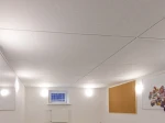Szerokokątne ujęcie jasnego pomieszczenia z nowoczesnym oświetleniem sufitowym LED z panelami akustycznymi.
