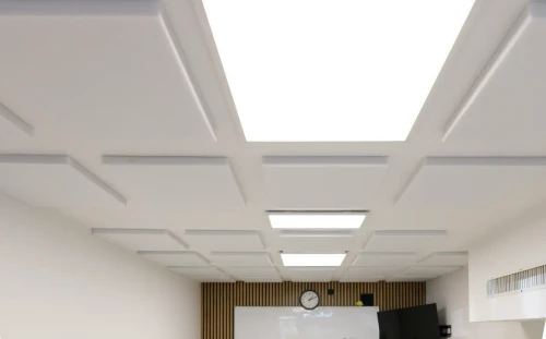 Ujęcie pod kątem na świecący panel LED z grafiką chmur wbudowany w sufit podwieszany.