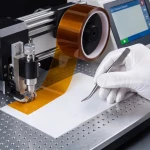 Proces druku 3D z wykorzystaniem izolacyjnej taśmy kaptonowej na stole roboczym drukarki.