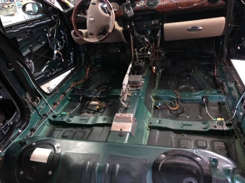 Rozebrane wnętrze kabiny Rover 75 z widoczną gołą blachą podłogi, przygotowane do kompleksowego wygłuszenia materiałami Bitmat