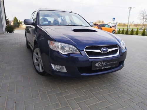 Ciemnoniebieskie Subaru Legacy zaparkowane przed warsztatem, przygotowane do kompleksowego wyciszenia i wygłuszania