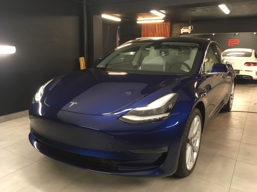 Niebieska Tesla Model 3 w hali warsztatowej, przygotowana do profesjonalnego wyciszenia drzwi