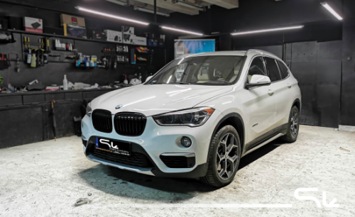 Białe BMW X1 zaparkowane na zewnątrz, przygotowane do wygłuszenia drzwi, nadkoli i maski materiałami Bitmat