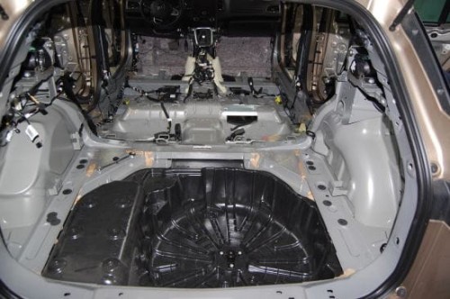 Rozebrana przestrzeń bagażnika i podłogi Renault Megane IV z widoczną gołą blachą przed rozpoczęciem wygłuszania