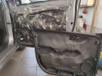 Zdemontowana plastikowa tapicerka drzwi Chevroleta Aveo zabezpieczona warstwą ciemnej pianki wygłuszającej Bitmat K6s
